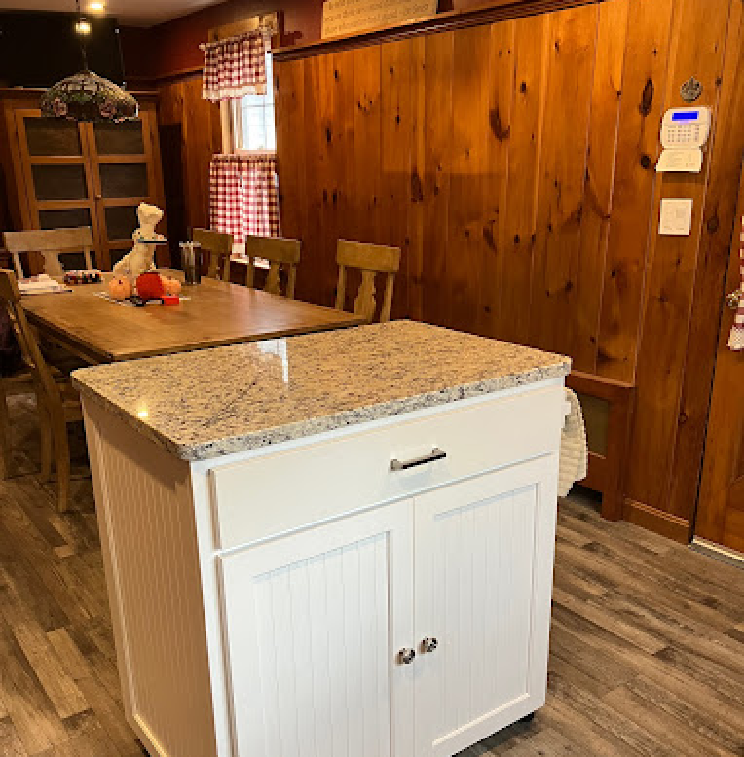 Small movable kitchen island and cart built in birch painted white with one drawer, bead board panels in the doors, sides, and back with granite counter top.