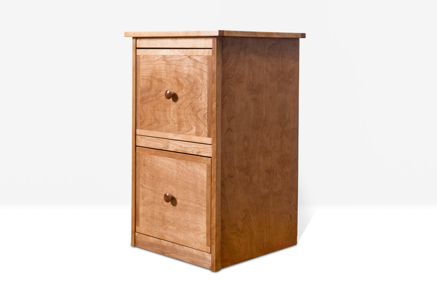 Angled view of a two drawer file cabinet with wood knobs in a light brown stain color.